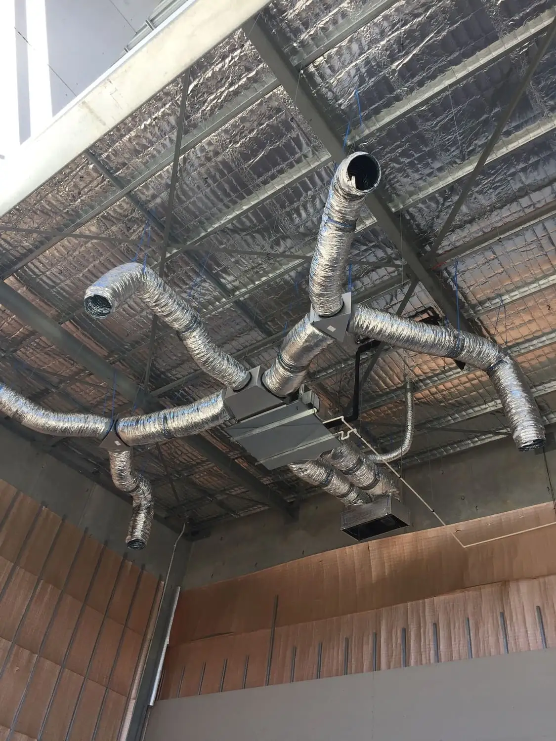 Insulated flexible ducting fanning out from a ceiling-mounted indoor unit in a commercial fit-out